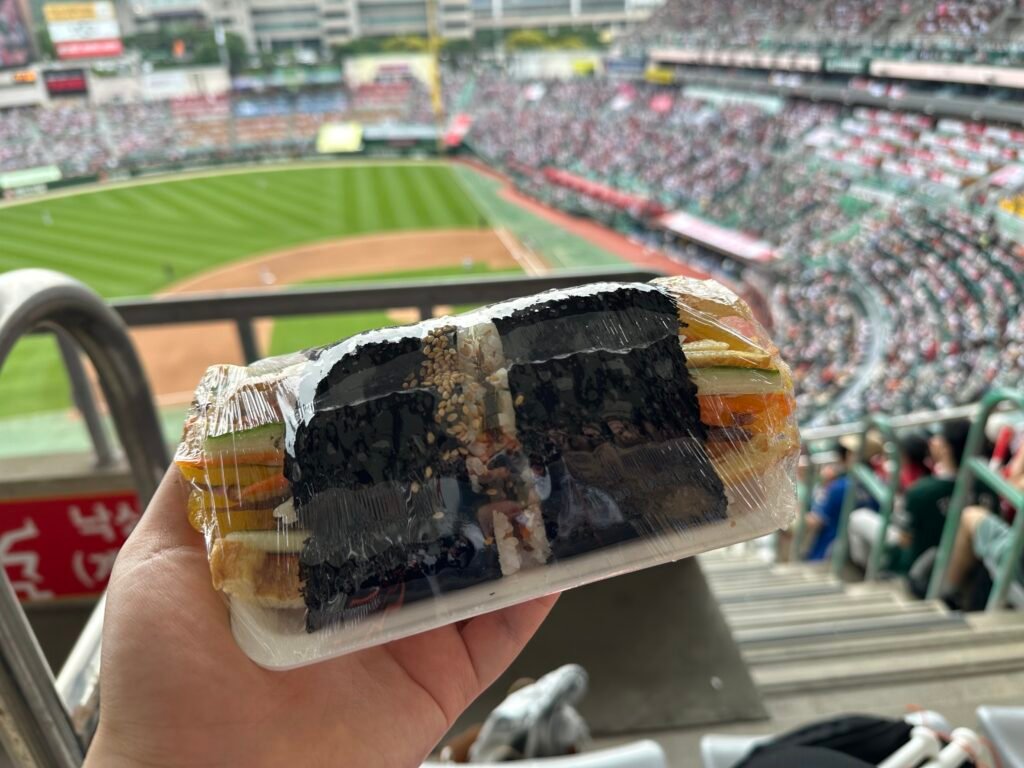 A pack of gimbap purchased to eat while watching a baseball game at the stadium.