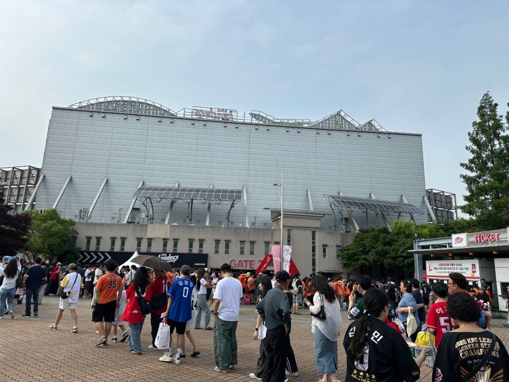 Crowds of people lining up to enter a baseball stadium in Korea, reflecting the growing popularity of baseball among fans.