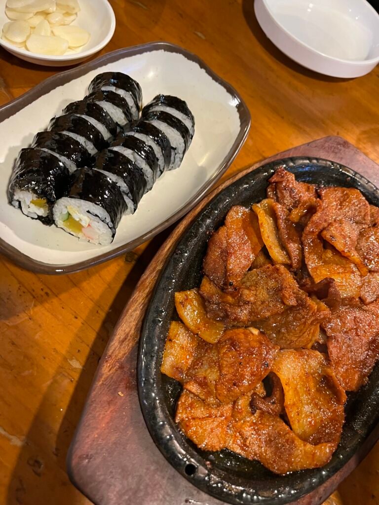 The rice and vegetables are rolled in seaweed into a long, cylindrical shape and neatly sliced into bite-sized round pieces.
The charcoal-grilled pork is coated in a red sauce and looks juicy and rich with oil.