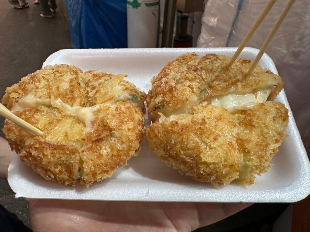 A handmade fish cake croquette cut into four pieces, with melted cheese flowing between them