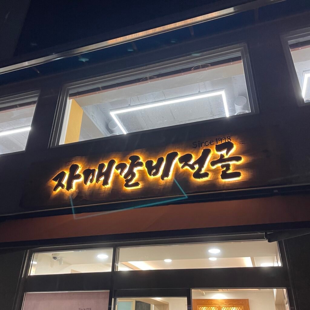 The Sister Galbi Jeongol sign glowing with a yellow border, with “Since 1998” written in small text