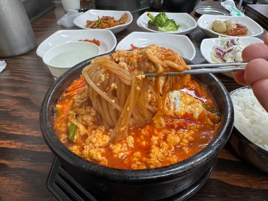 Chewy jjolmyeon noodles revealed under the cheese in Cheese Jjolmyeon Sundubu