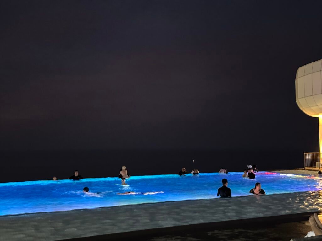 A night view of the hotel pool illuminated by blue underwater lights