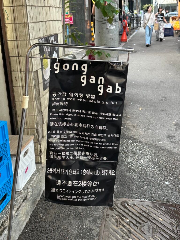 A sign explaining the waiting procedure at Gonggan-gap, instructing guests to line up from the sign toward the nearby utility pole.