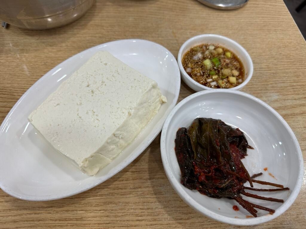 Square-shaped Modubu tofu served with perilla leaf pickles and soy sauce on the side