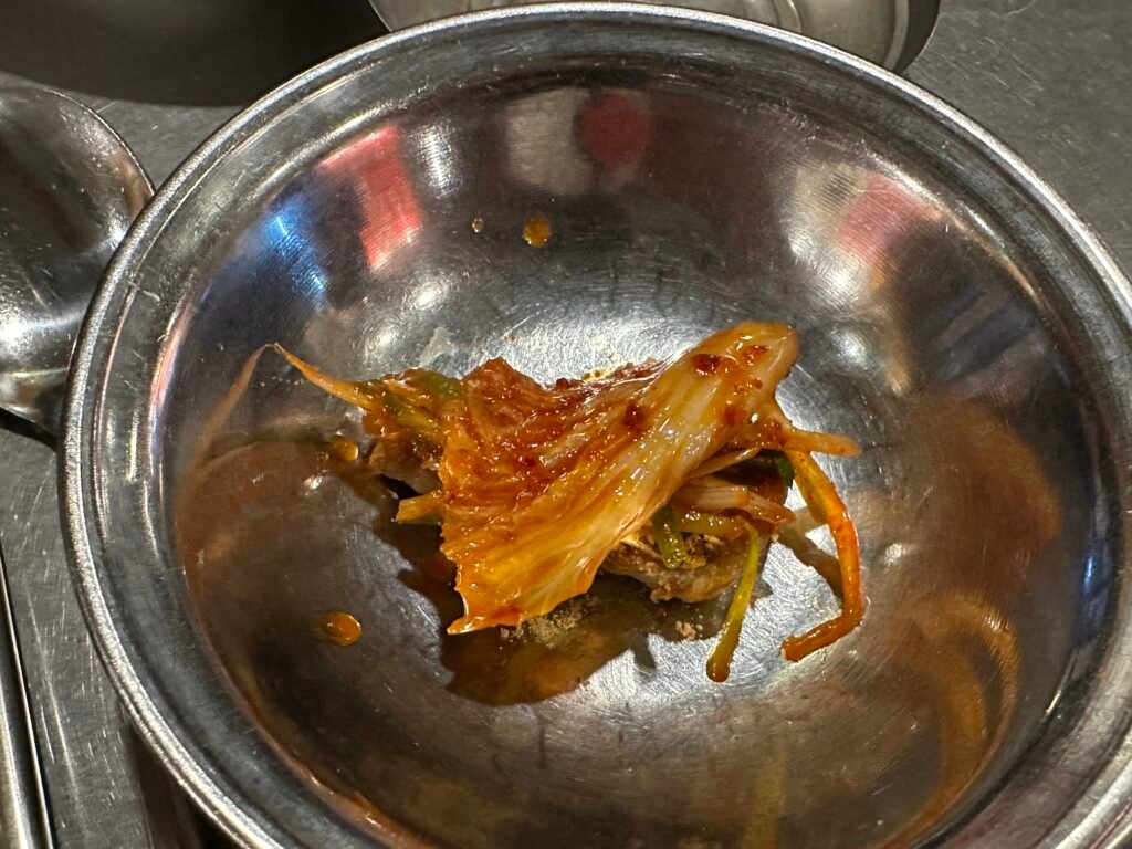 Pork belly coated in soybean powder topped with green onion salad and stir-fried kimchi