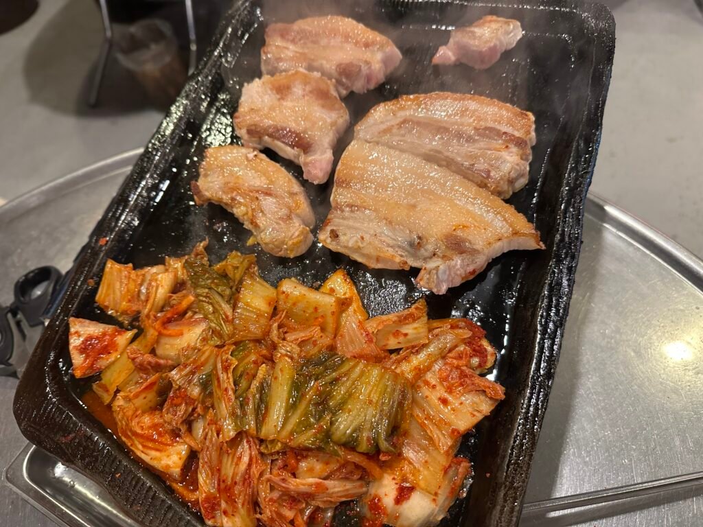 Grilled pork being flipped over the fire, cooked evenly and glowing with a golden-brown color